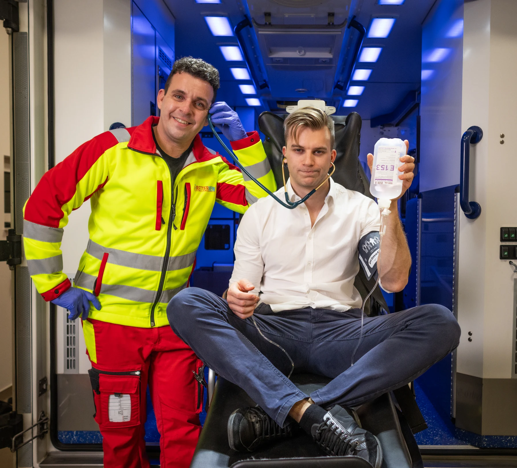 Samy und Max bei einer humorvollen, gestellten Fotosession im Rettungswagen